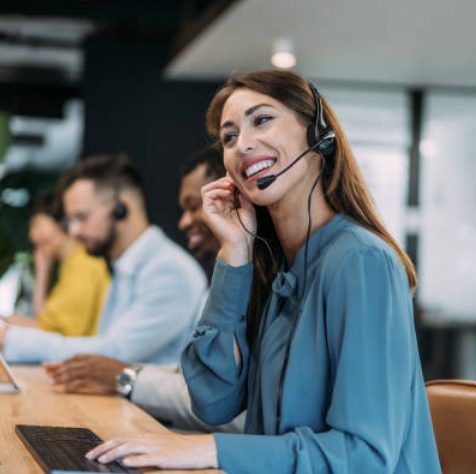 Une conseillère au casque téléphonique sourit à son poste de travail